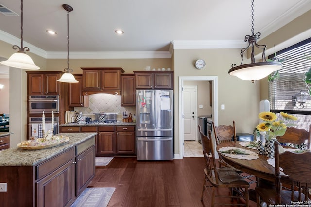 kitchen featuring decorative backsplash, visible vents, ornamental molding, hanging light fixtures, and appliances with stainless steel finishes