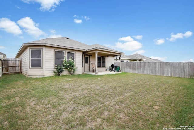 rear view of property featuring a yard, a fenced backyard, and a patio area