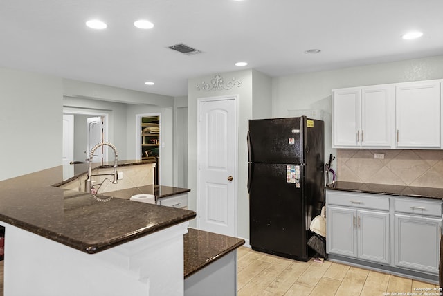 kitchen featuring visible vents, tasteful backsplash, light wood-type flooring, and freestanding refrigerator