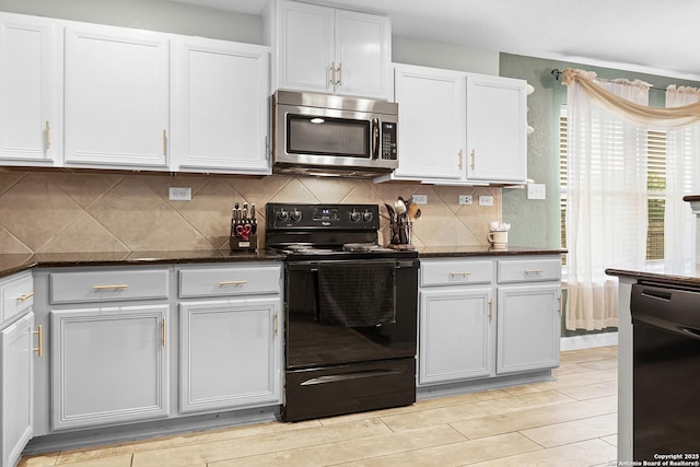 kitchen featuring black appliances, dark stone counters, white cabinets, and backsplash