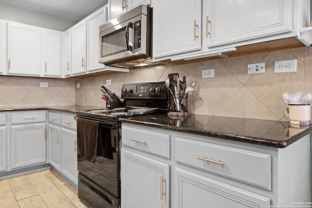 kitchen with stainless steel microwave, white cabinets, electric range, and dark stone counters
