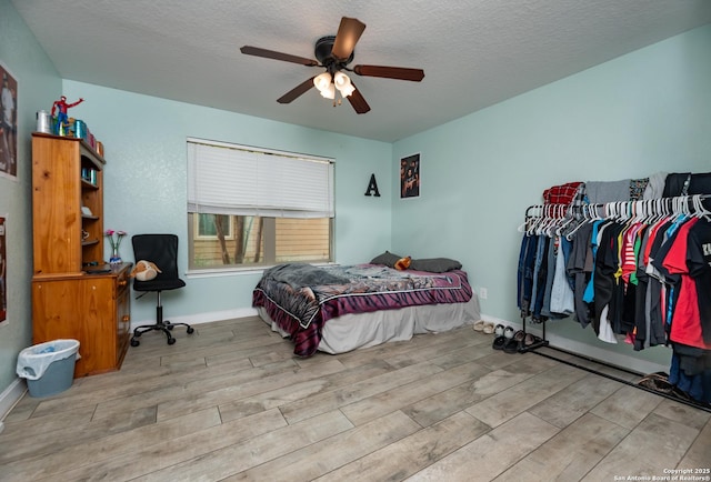 bedroom with baseboards, wood finished floors, a ceiling fan, and a textured ceiling