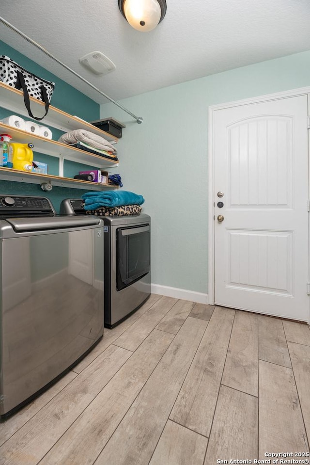 laundry room featuring washer and dryer, light wood-style flooring, laundry area, and baseboards