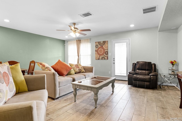 living room featuring ceiling fan, visible vents, and light wood-type flooring