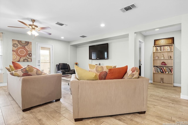 living area with visible vents, a ceiling fan, light wood finished floors, and baseboards