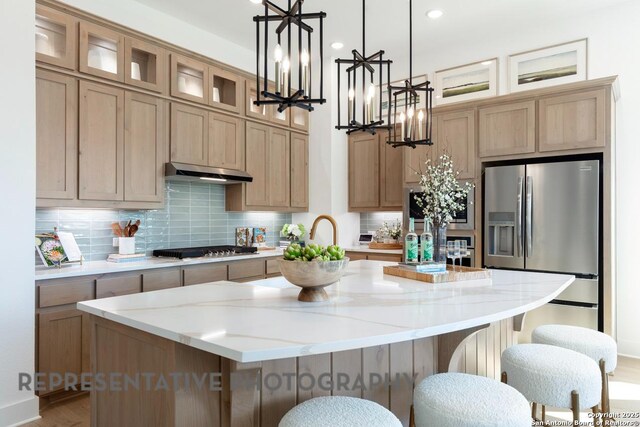 349 Hulda, New Braunfels, TX 78130 - kitchen featuring a chandelier, stainless steel appliances, under cabinet range hood, a kitchen breakfast bar, and a center island with sink