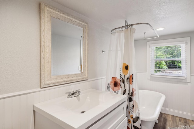 bathroom featuring vanity, a freestanding tub, wood finished floors, a shower with shower curtain, and a textured ceiling