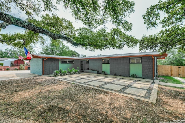 rear view of house with fence, a patio, and brick siding