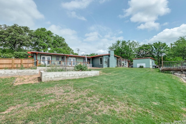 rear view of property with a lawn and fence