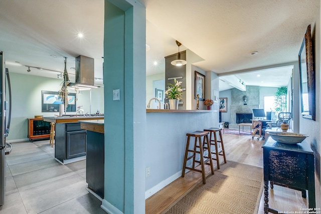 kitchen featuring open floor plan, island exhaust hood, stainless steel appliances, and baseboards