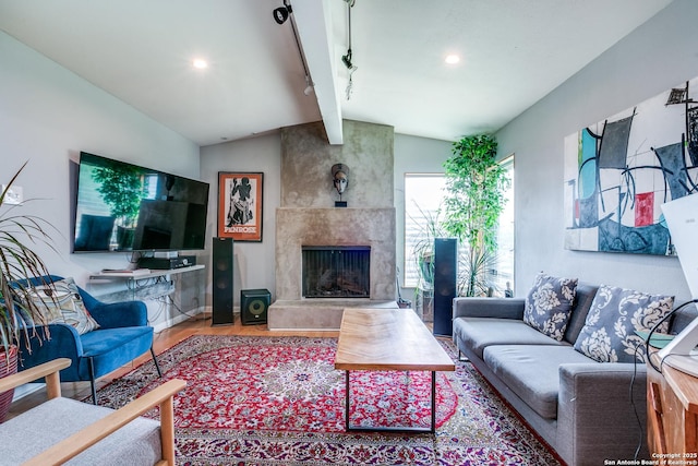 living room with rail lighting, recessed lighting, a fireplace, wood finished floors, and vaulted ceiling with beams