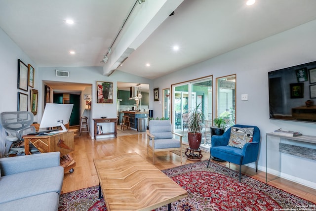 living room featuring visible vents, light wood-style flooring, and vaulted ceiling with beams