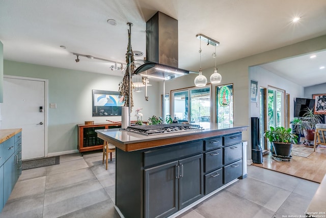 kitchen featuring stainless steel gas cooktop, island exhaust hood, blue cabinetry, a center island, and pendant lighting