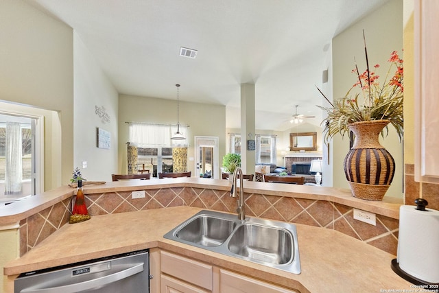 kitchen featuring a sink, visible vents, open floor plan, dishwasher, and a fireplace