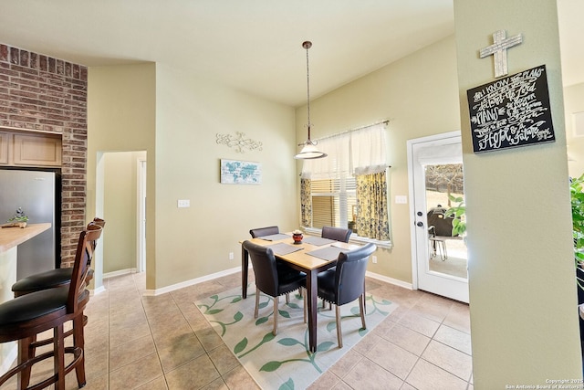 dining space with light tile patterned flooring, high vaulted ceiling, and baseboards