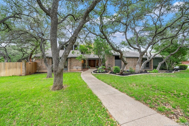 mid-century inspired home with brick siding, a front lawn, and fence
