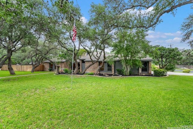 mid-century inspired home with fence, brick siding, and a front yard