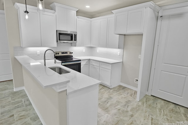 kitchen featuring stainless steel appliances, decorative backsplash, a peninsula, and a sink