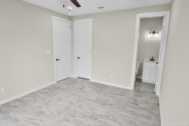 unfurnished bedroom with baseboards, visible vents, and ensuite bath