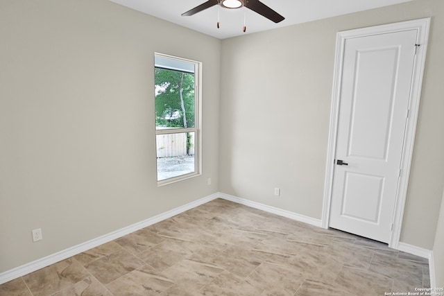 empty room featuring ceiling fan and baseboards