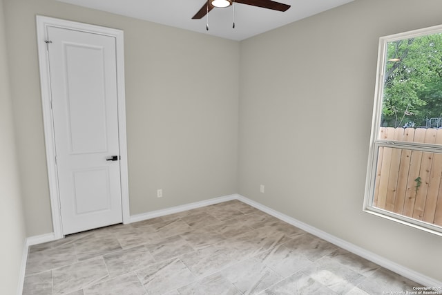 empty room with a ceiling fan and baseboards