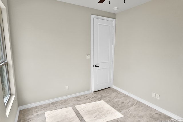unfurnished room with a ceiling fan and baseboards