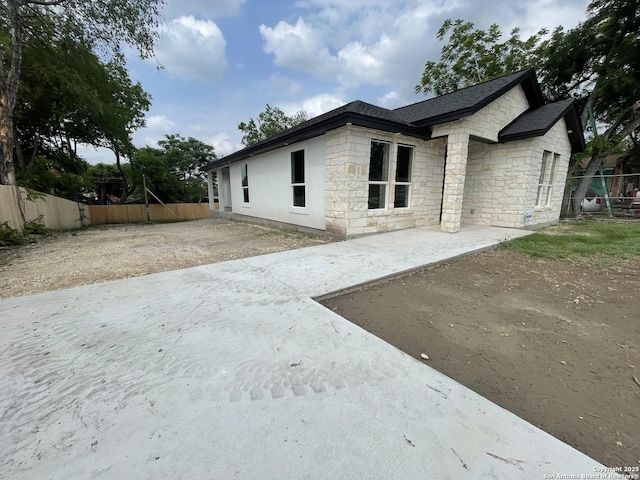 exterior space with a patio, fence, and stone siding