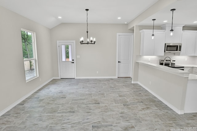 kitchen with a notable chandelier, tasteful backsplash, light countertops, white cabinets, and appliances with stainless steel finishes