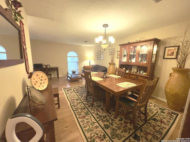 dining space with a chandelier, light wood-type flooring, and baseboards