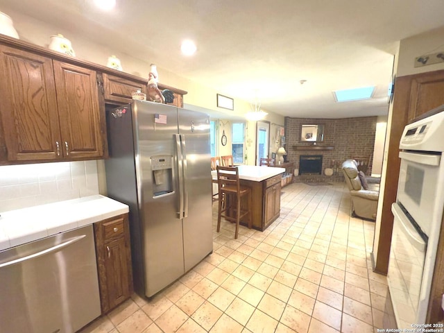 kitchen featuring light countertops, open floor plan, appliances with stainless steel finishes, and a fireplace