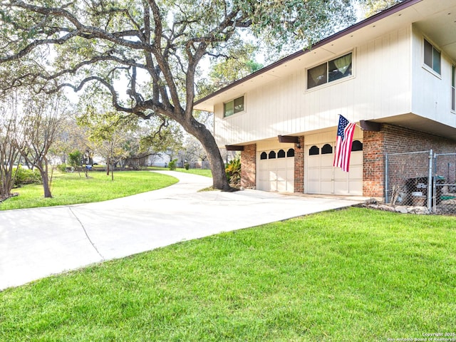 exterior space with a yard, brick siding, concrete driveway, an attached garage, and fence