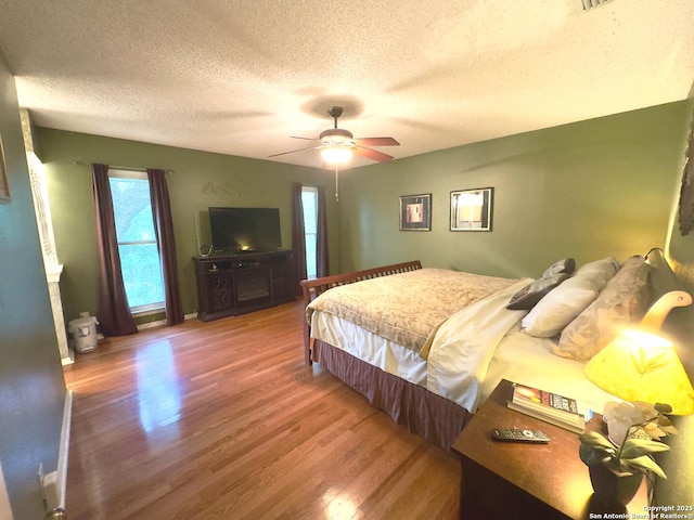 bedroom with wood finished floors, a ceiling fan, and a textured ceiling