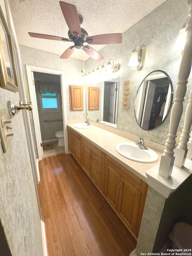 bathroom featuring toilet, a textured ceiling, a sink, and wood finished floors