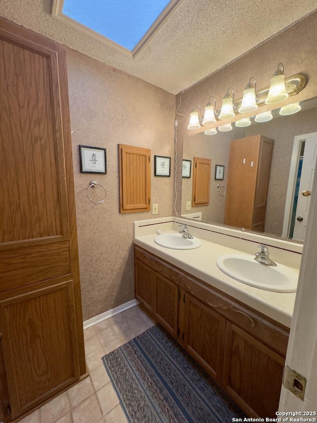 full bathroom featuring double vanity, a sink, a skylight, and a textured ceiling