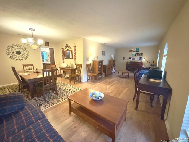 living room featuring visible vents, a notable chandelier, baseboards, and light wood-style floors