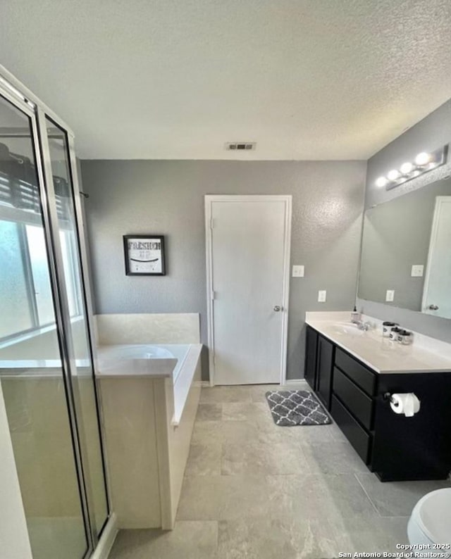 bathroom featuring a textured ceiling, visible vents, a stall shower, a garden tub, and vanity