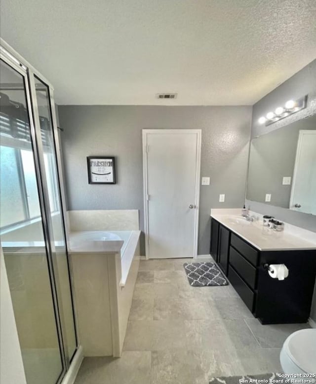 full bathroom with vanity, a stall shower, visible vents, a garden tub, and a textured ceiling