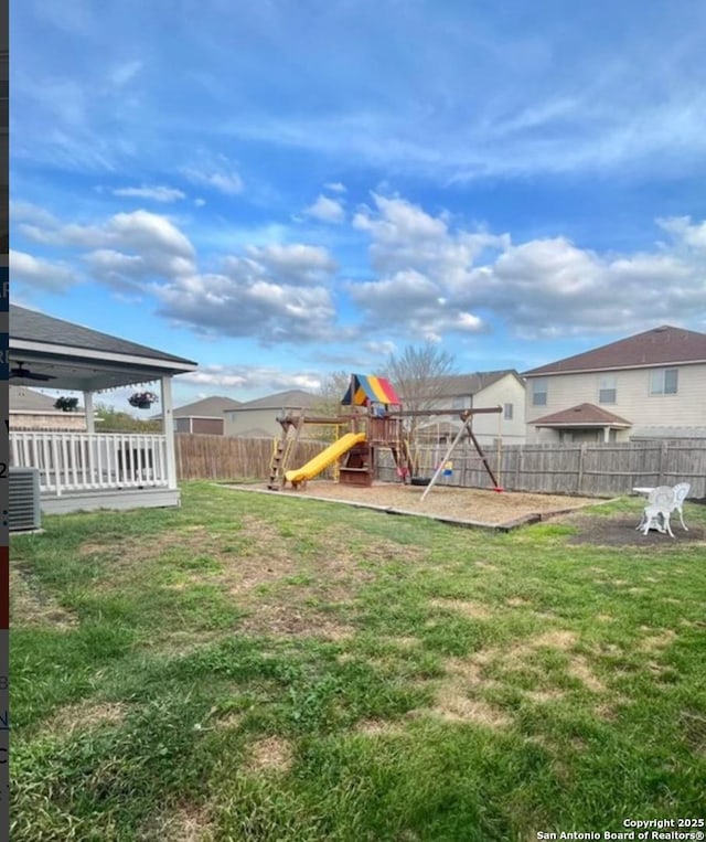 view of yard featuring a playground, a fenced backyard, and central AC unit