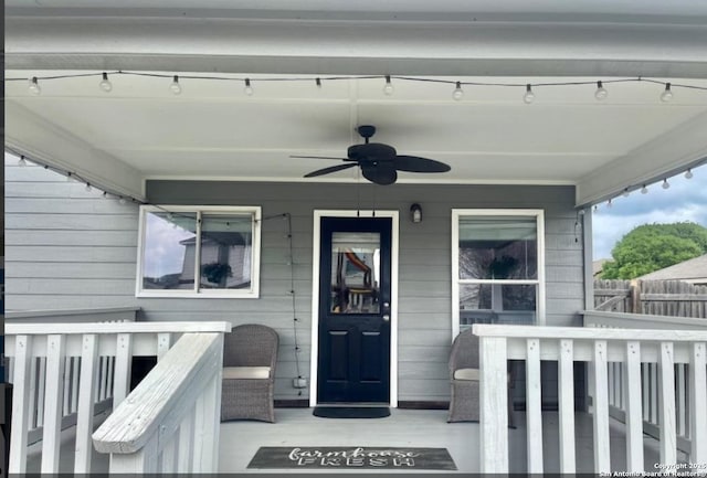 doorway to property featuring a porch, a ceiling fan, and fence