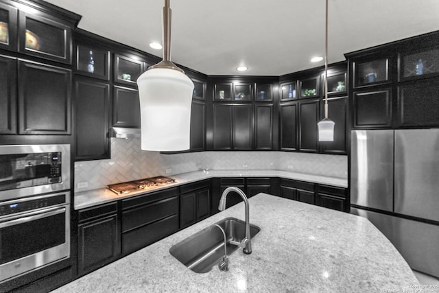 kitchen with dark cabinets, backsplash, stainless steel appliances, and a sink