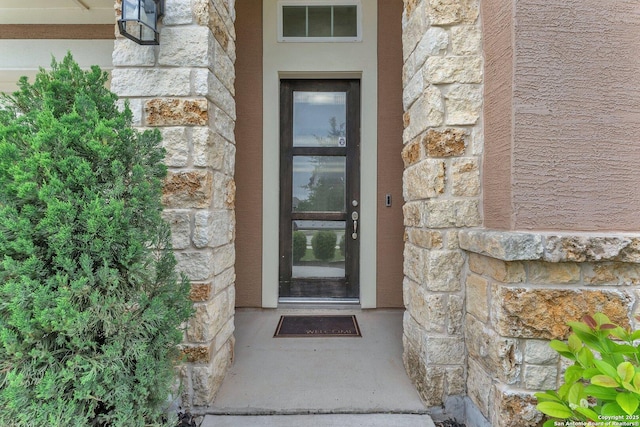 property entrance with stone siding and visible vents