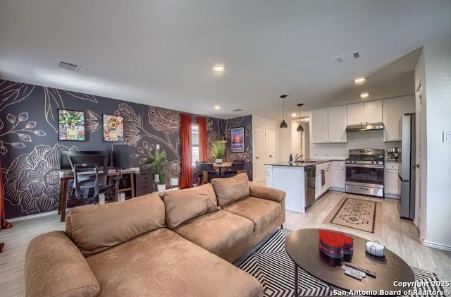living area featuring visible vents, light wood-type flooring, recessed lighting, and wallpapered walls