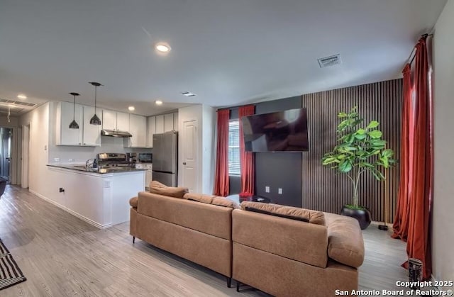 living area with visible vents, light wood-style flooring, and recessed lighting