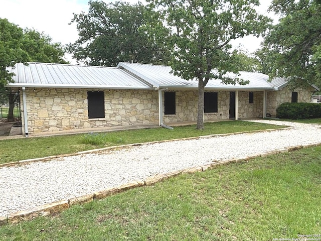 ranch-style house featuring a front lawn, metal roof, and stone siding