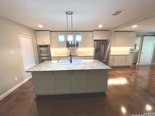 kitchen with a sink, stainless steel appliances, visible vents, backsplash, and baseboards