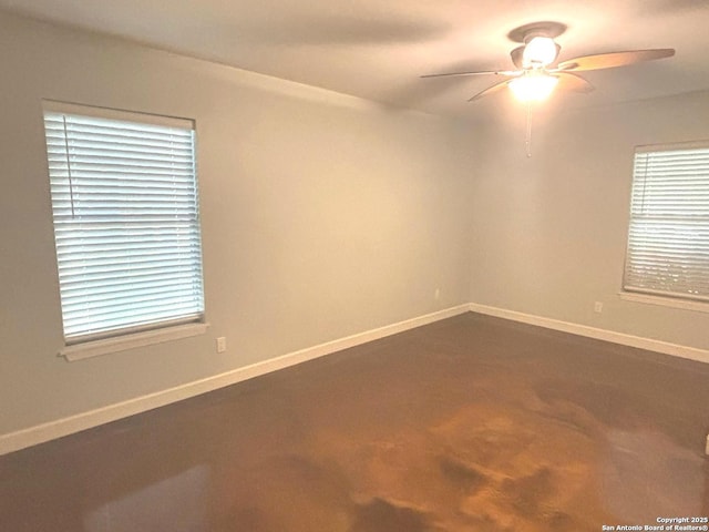 empty room featuring a ceiling fan and baseboards