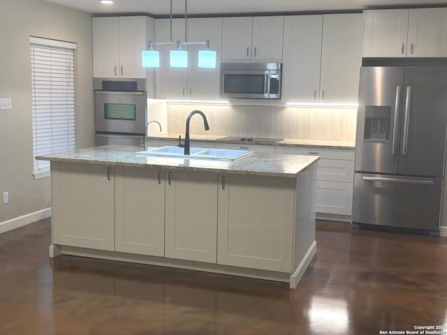 kitchen with an island with sink, stainless steel appliances, backsplash, a sink, and baseboards