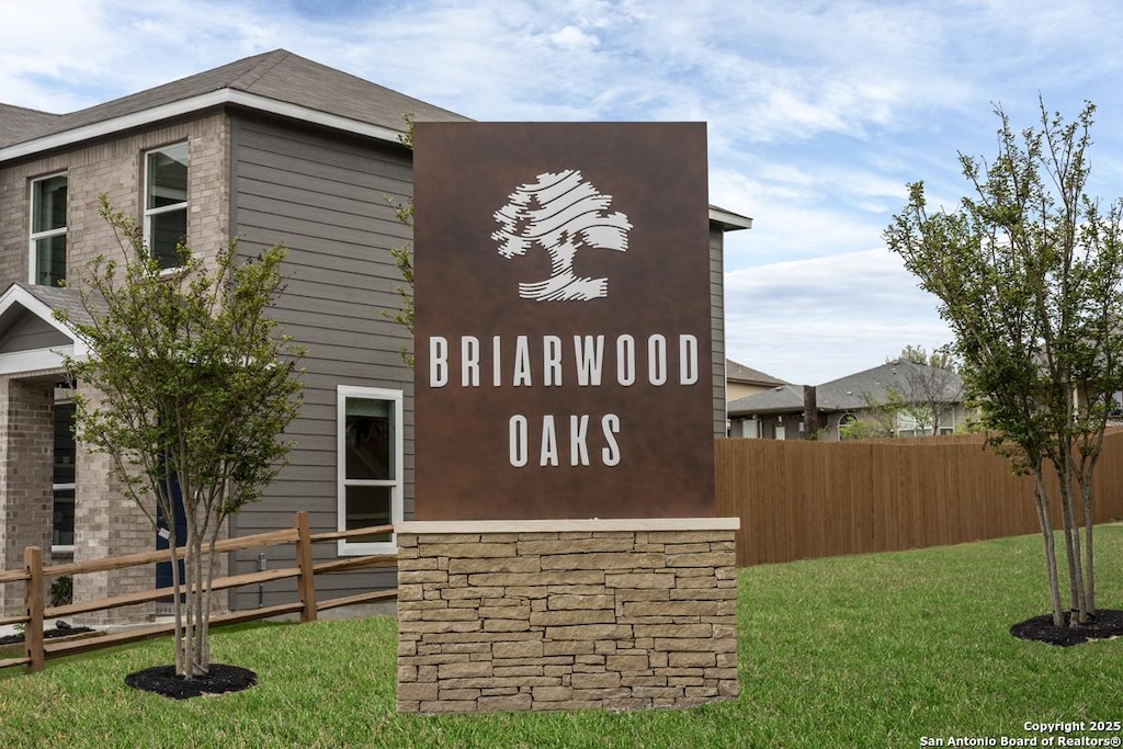 community / neighborhood sign with a yard and fence
