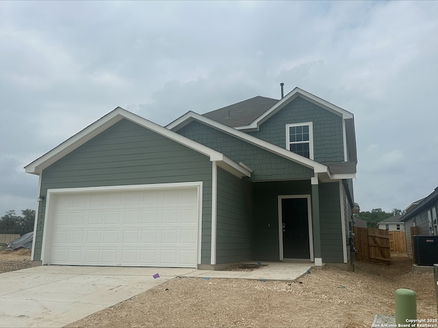 view of front of house featuring central AC, fence, concrete driveway, and an attached garage