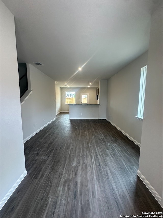 unfurnished living room featuring baseboards, visible vents, dark wood-style floors, and recessed lighting
